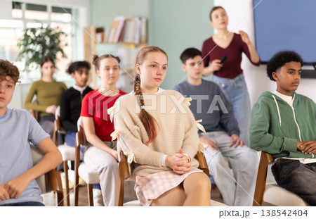 Teenage students listening to lecture while teacher stands in background Teenage students listening to lecture while teacher stands in background 138542404