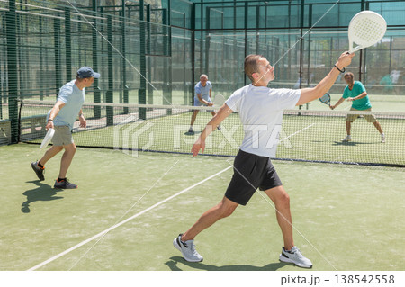 Men play padel on an outdoor tennis court. Hitting the ball with racket 138542558