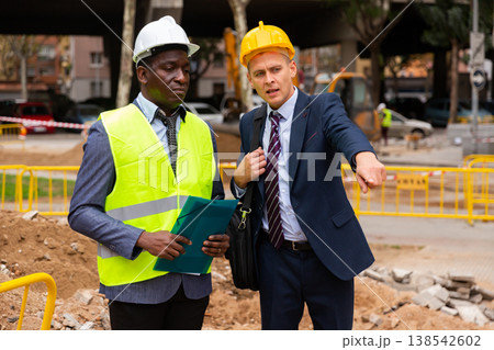 Engineer and architect are discussing options for laying a pipe on street Engineer and architect are discussing options for laying a pipe on street 138542602