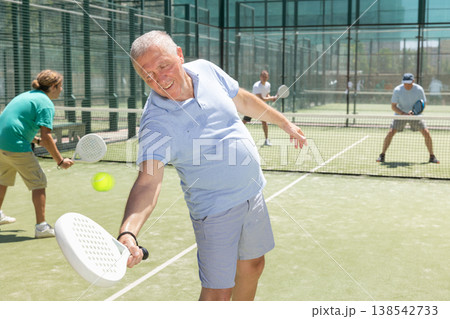 Adult and elderly men playing padel against two men Adult and elderly men playing padel against two men 138542733