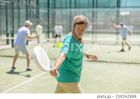 Adult and elderly men playing padel against two men 138542884