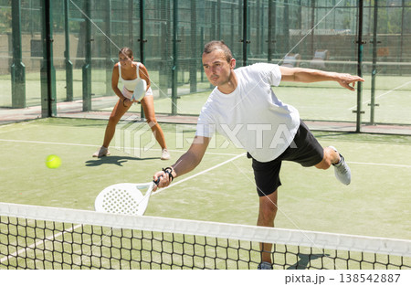 Young woman and man playing doubles padel 138542887