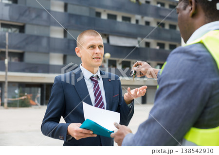 Engineer giving keys to new apartment to man Engineer giving keys to new apartment to man 138542910