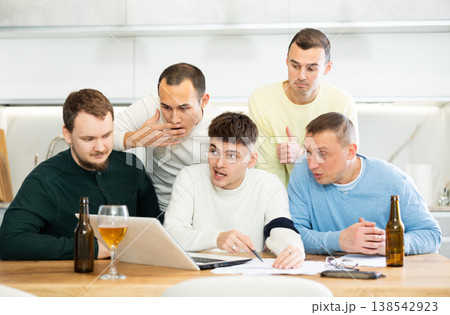 Group of football fans drinking beer and watching football match on laptop at home Group of football fans drinking beer and watching football match on laptop at home 138542923