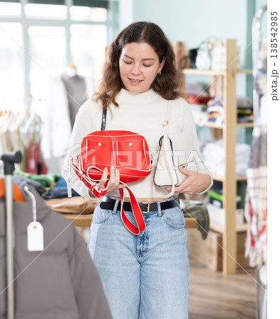 Woman carefully choosing a stylish bag in the store Woman carefully choosing a stylish bag in the store 138542985