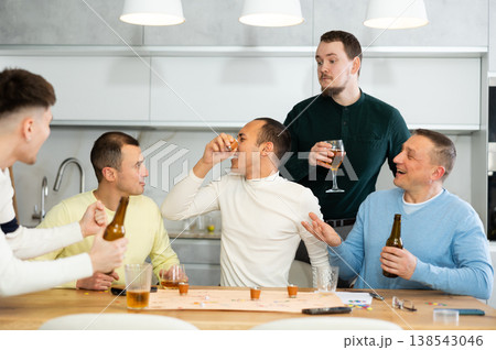 Defeated man taking shot while playing drinking board game with friends 138543046
