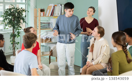 Teenage boy stands in a circle in front of other schoolchildren with a speech. 138543059
