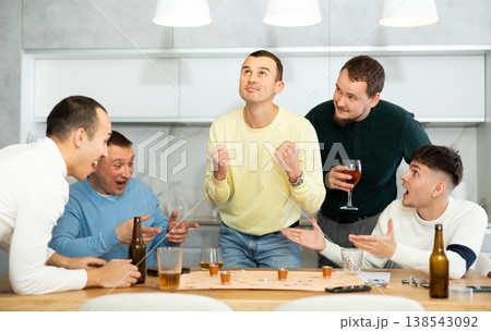 Group of cheerful men engaged in alcohol-fueled board game Group of cheerful men engaged in alcohol-fueled board game 138543092