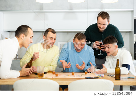 Group of cheerful men engaged in alcohol-fueled board game Group of cheerful men engaged in alcohol-fueled board game 138543094