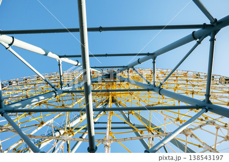 Wide angle view looking up into the radial symmetry of the yellow and blue metal giant wheel framework 138543197