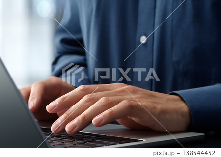 オフィスのデスクでノートパソコンを使うビジネスパーソン。手とキーボードのクローズアップ。ビジネスでの 138544452