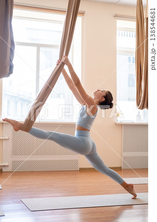 Woman fitness. Stretching exercise. Athlete doing fly yoga split pose holding fabric hammock straps for support flexibility workout. 138544681