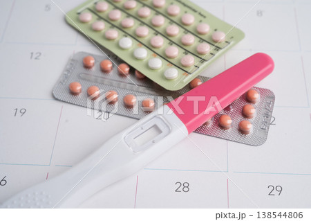 Pregnancy test and condom for female on calendar, ovulation day. Pregnancy test and condom for female on calendar, ovulation day. 138544806