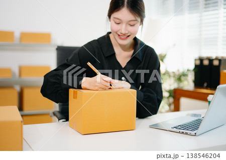 Startup small business SME, Entrepreneur owner woman using smartphone or tablet taking receive and checking online purchase shopping order to preparing pack product box. Startup small business SME, Entrepreneur owner woman using smartphone or tablet taking receive and checking online purchase shopping order to preparing pack product box. 138546204