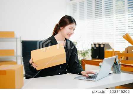 Young businesswoman managing online sales and shipping from a modern home office. Perfect for showcasing technology Young businesswoman managing online sales and shipping from a modern home office. Perfect for showcasing technology 138546206