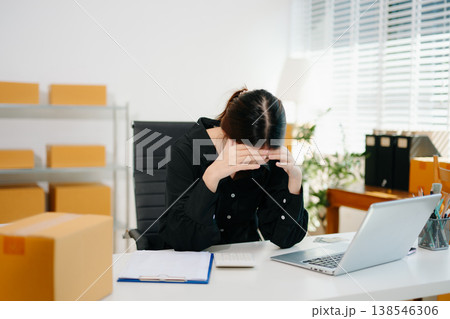 Stressed Asian woman sitting at office desk with parcels and laptop, overwhelmed by online business problems, workload pressure Stressed Asian woman sitting at office desk with parcels and laptop, overwhelmed by online business problems, workload pressure 138546306