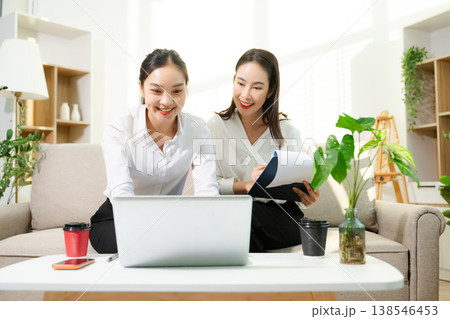 Two professional businesswomen working together with laptop, coffee and smartphone at home office. Remote work, startup teamwork, modern business lifestyle. Two professional businesswomen working together with laptop, coffee and smartphone at home office. Remote work, startup teamwork, modern business lifestyle. 138546453