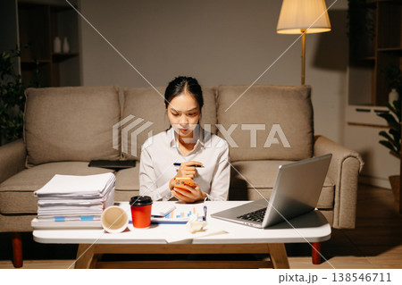 Stressed businesswoman working late at home with laptop and paperwork. Deadline pressure, overtime, workload, finance and modern business lifestyle concept. Stressed businesswoman working late at home with laptop and paperwork. Deadline pressure, overtime, workload, finance and modern business lifestyle concept. 138546711