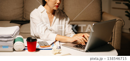 Stressed Asian woman using calculator and laptop for financial accounting and tax report late at night at home. 138546715