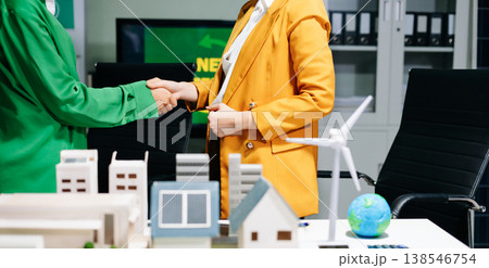 Businesswomen shaking hands in a green office with renewable energy models, net zero and ESG concept, sustainability, clean energy Businesswomen shaking hands in a green office with renewable energy models, net zero and ESG concept, sustainability, clean energy 138546754
