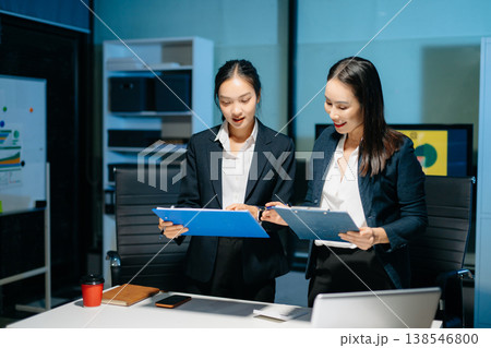 Two professional businesswomen analyzing reports and planning strategy at office desk. Teamwork, collaboration, management, consulting and modern corporate workplace. 138546800