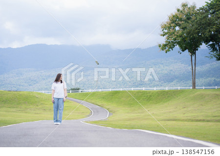 Relax and wellness concept with woman walk on road in garden and mountain background at chiangmai thailand in raining season 138547156
