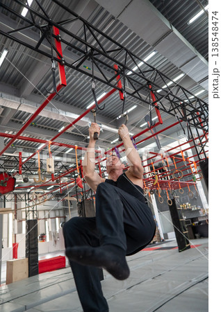 An athletic man practices at a ninja club's indoor obstacle course. An athletic man practices at a ninja club's indoor obstacle course. 138548474