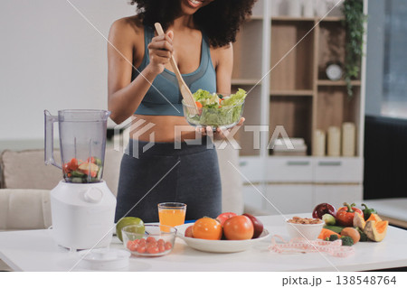 Young nutritionist showing bell peppers during an online video call consulting about healthy eating, sitting at home at a table with vegetables, laptop and measuring tape Young nutritionist showing bell peppers during an online video call consulting about healthy eating, sitting at home at a table with vegetables, laptop and measuring tape 138548764