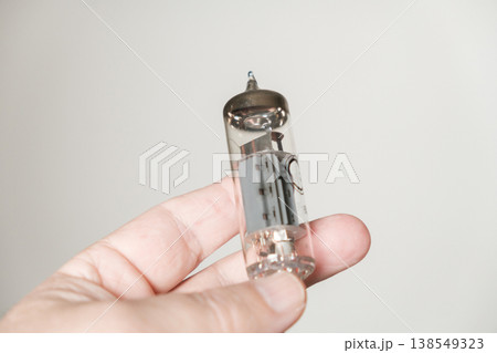 A vacuum tube, held in a hand, in close-up. A vacuum tube, held in a hand, in close-up. 138549323