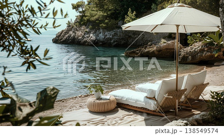 lifestyle photography, beach lounge with white linen and wicker furniture on the shore of a mediterranean cove where there is an umbrella to shading from the sun lifestyle photography, beach lounge with white linen and wicker furniture on the shore of a mediterranean cove where there is an umbrella to shading from the sun 138549574