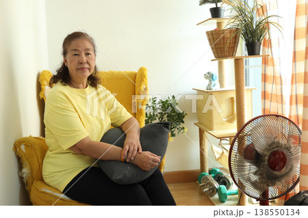 Senior Woman with Cushion on Yellow Chair 138550134