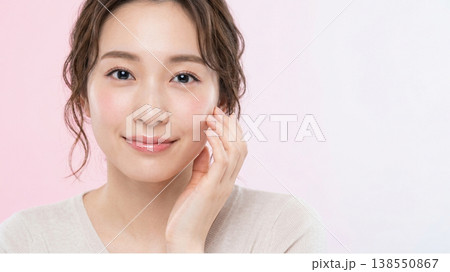 スキンケア・美容:頬に手を添えて微笑む女性とピンクのコピースペース スキンケア・美容:頬に手を添えて微笑む女性とピンクのコピースペース 138550867