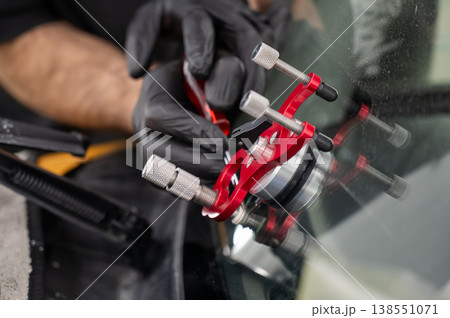 A technician injects resin into a windshield crack. A technician injects resin into a windshield crack. 138551071
