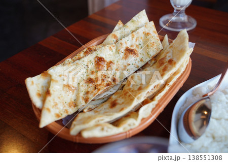 Freshly baked Garlic Naan bread served in a traditional basket on a wooden table. Freshly baked Garlic Naan bread served in a traditional basket on a wooden table. 138551308