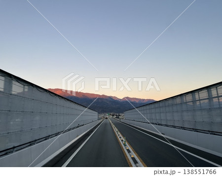 夕暮れの山へ続くバイパス道路 直線構図のドライブ風景 夕暮れの山へ続くバイパス道路 直線構図のドライブ風景 138551766