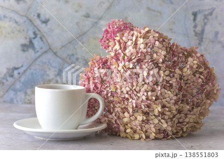 White cup of coffee or tea and pink hydrangea flower on a gray marble background White cup of coffee or tea and pink hydrangea flower on a gray marble background 138551803