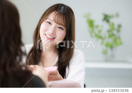 ネイルサロンで施術を行うネイリストの女性スタッフの丁寧な接客と美容サービスやカウンセリングのイメージ ネイルサロンで施術を行うネイリストの女性スタッフの丁寧な接客と美容サービスやカウンセリングのイメージ 138553036