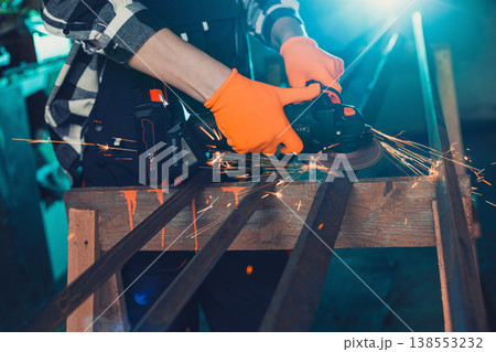 A man cuts metal using an angle grinder. Many sparks 138553232