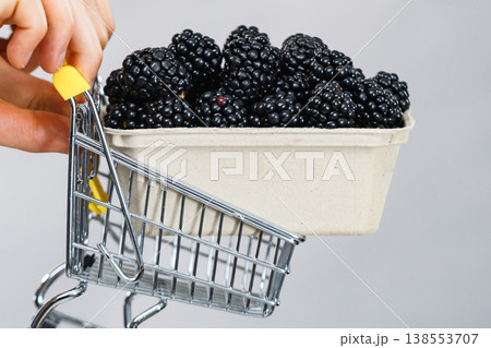 Hand holds blackberry fruits in shopping cart Hand holds blackberry fruits in shopping cart 138553707