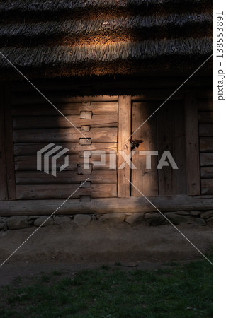 Sunlit rustic wooden cabin with thatched roof and old door Sunlit rustic wooden cabin with thatched roof and old door 138553891