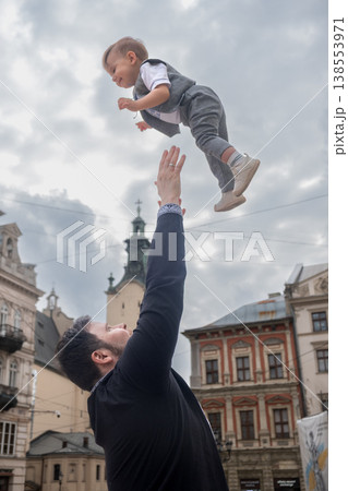Father tossing toddler in the air in historic city square Father tossing toddler in the air in historic city square 138553971