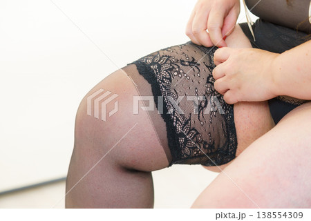 Woman plus size puts on black nylon stockings Woman plus size puts on black nylon stockings 138554309