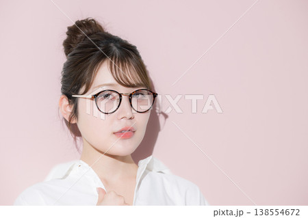 ピンク背景で眼鏡（サングラス）が似合うお団子ヘアのかわいい美人な美容やビューティーイメージ 138554672