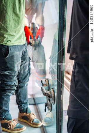 Large window glass panel with suction cup lifters prepared for installation or replacement in apartment interior. Professional window repair service, home maintenance and renovation concept. Large window glass panel with suction cup lifters prepared for installation or replacement in apartment interior. Professional window repair service, home maintenance and renovation concept. 138554969