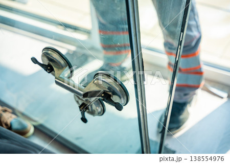 Close up of suction cup lifter attached to window glass used for safe handling during replacement process in apartment. Professional equipment for glass installation and repair work concept. Close up of suction cup lifter attached to window glass used for safe handling during replacement process in apartment. Professional equipment for glass installation and repair work concept. 138554976