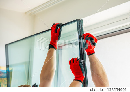 Worker separating triple glazed window glass unit into individual panels for safe handling and disposal after damage in apartment. Window repair, glass recycling and maintenance process concept. 138554991