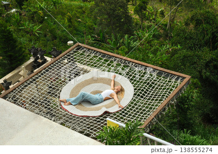 Person relaxes on a net above green landscapes in Bali Person relaxes on a net above green landscapes in Bali 138555274