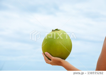 Person holds a green coconut at the beach in Bali Person holds a green coconut at the beach in Bali 138555282