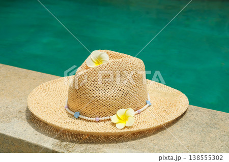 A straw hat with flowers rests on the edge of a pool in Bali A straw hat with flowers rests on the edge of a pool in Bali 138555302
