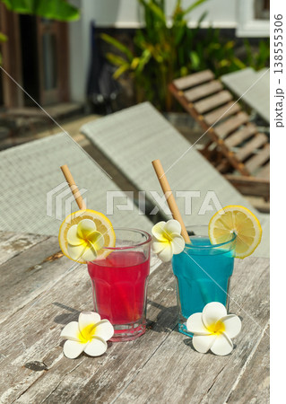Two colorful drinks sit on a table near sun loungers 138555306